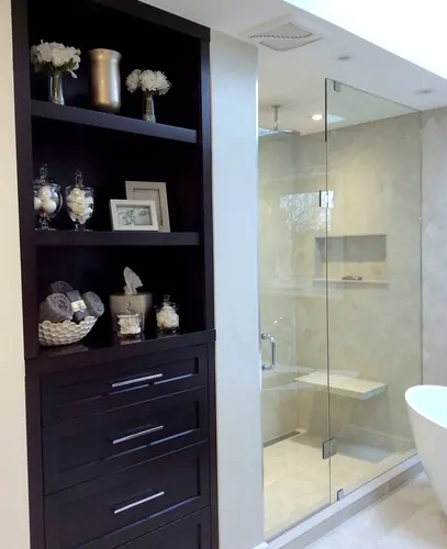 Dark espresso built-in with open display shelves and shaker drawers fronted by brushed nickel bar pulls, styled with apothecary jars beside a glass steam shower with mosaic-tiled walls — custom vanity hand-built by Classic Woodworking & Vanity in Toronto, Ontario