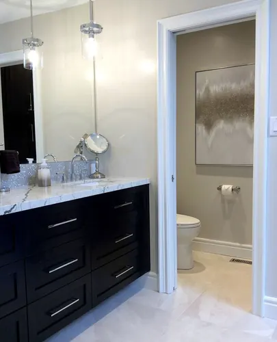 Espresso shaker vanity with chrome bar pulls under a white-and-grey marble counter and mosaic backsplash, glass pendant light and a mirror over the undermount sink beside the water closet — custom vanity hand-built by Classic Woodworking & Vanity in Burlington, Ontario